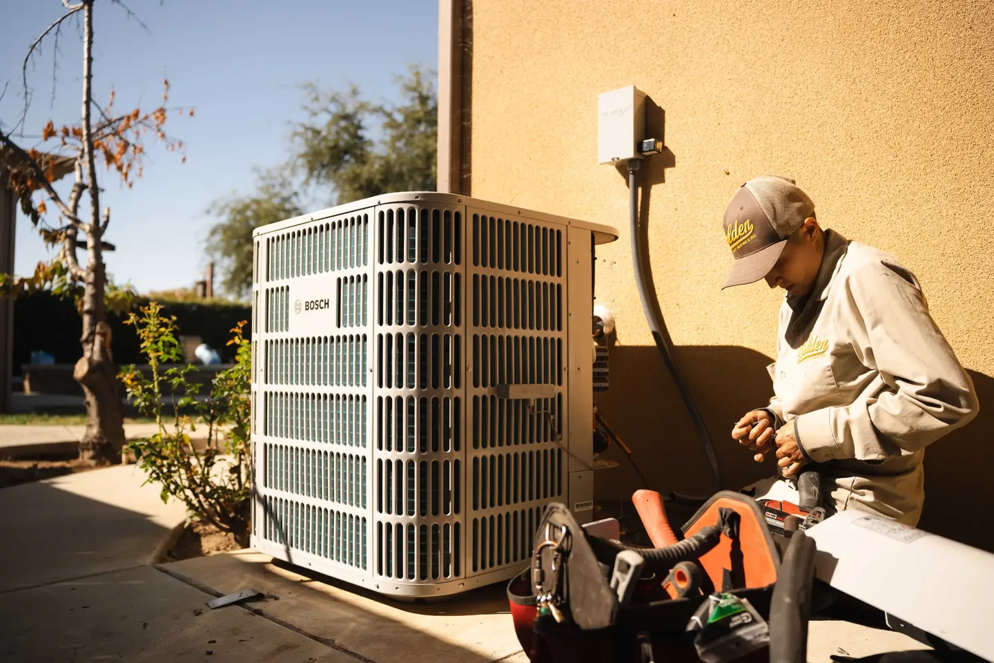 Golden Valley Heating and Air technician servicing outdoor air conditioning equipment — photo 1